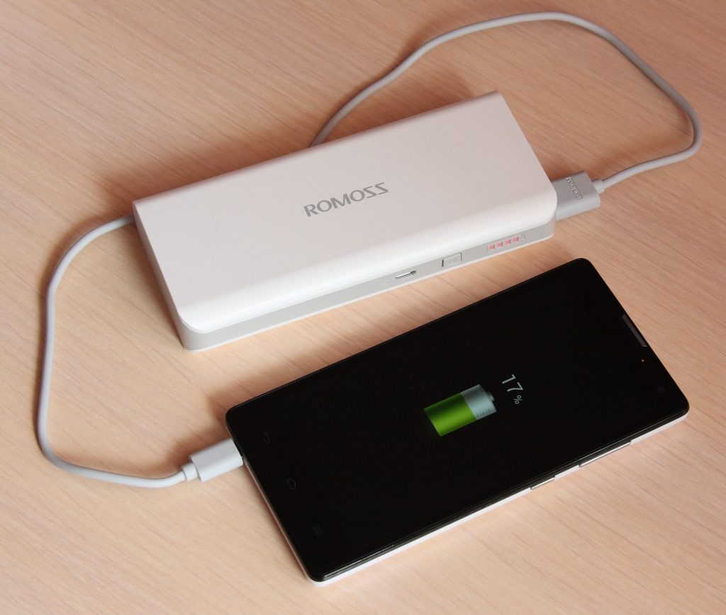A smartphone being charged from a portable power bank.