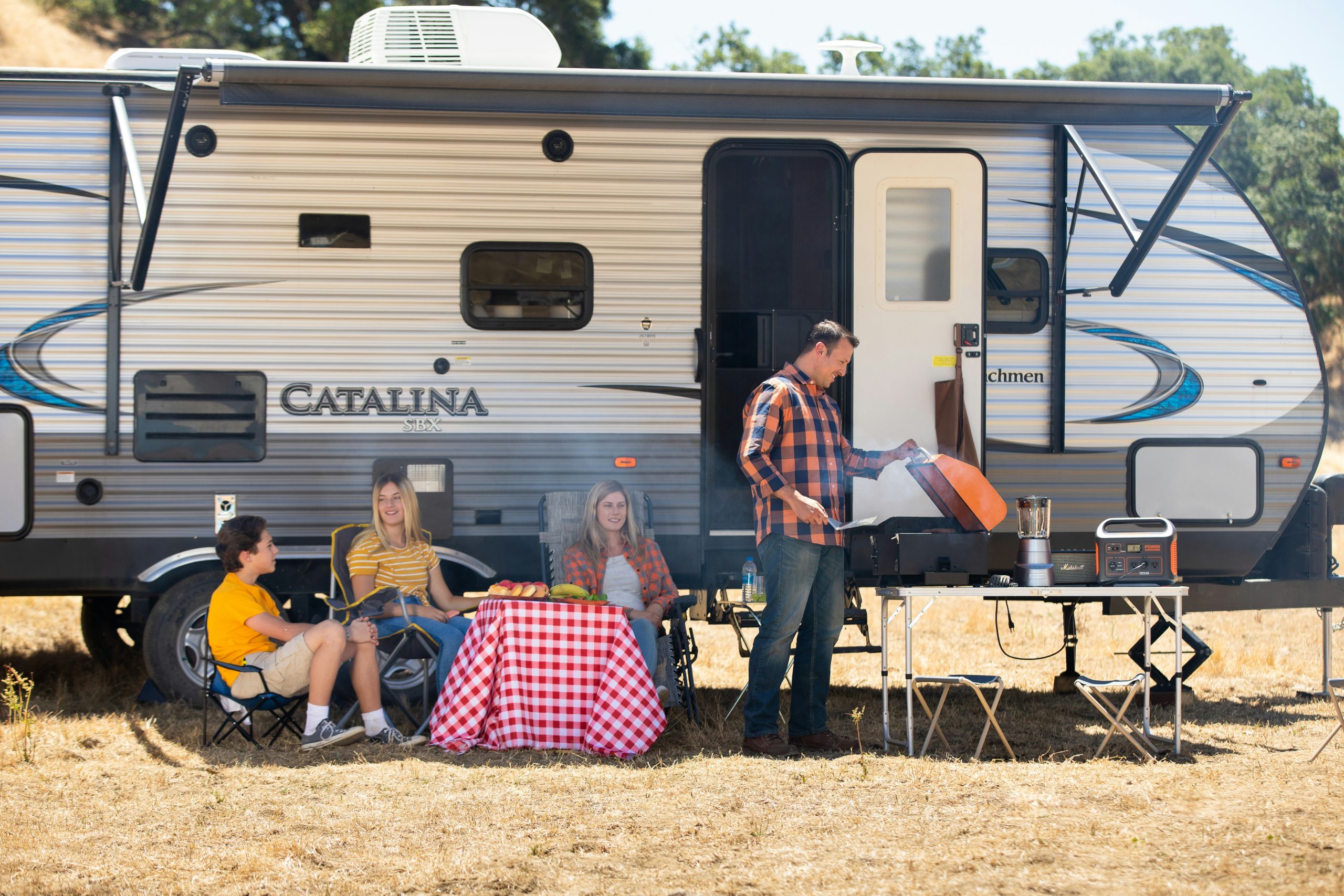 Portable power station near camper and solar panel (illustrative)