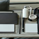 AI-generated airport travel essentials flat lay with organizer pouch, tracker, power bank, bottle and blank travel documents
